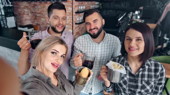 Adorable Blonde Woman Smiling Taking Selfie Surrounded By Friend Posing with Beer and Fast Food