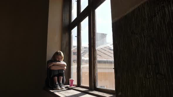 Pensive girl sitting on a window sill