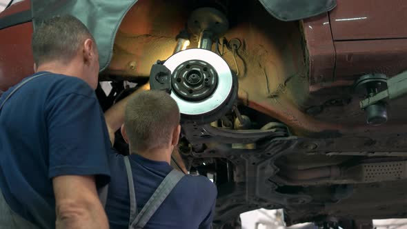 Two Mechanics Repairing Old Car Hub Breakers