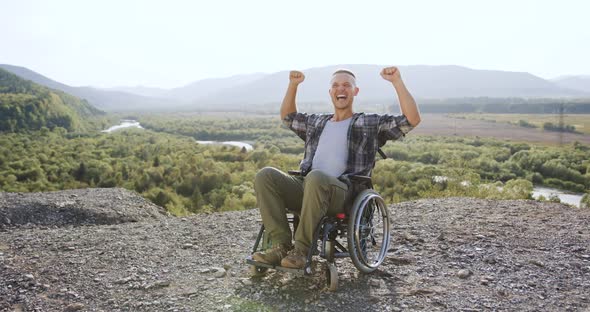 Disabled Guy in Wheelchair Raised His Hands on the Mount in Surrounded Wonderful Nature