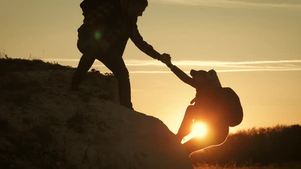 Silhouette of Helping Hand Between Two Climber. Two Hikers on Top of the Mountain