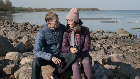 Couple Hugging While Sitting on a Rock at Coast