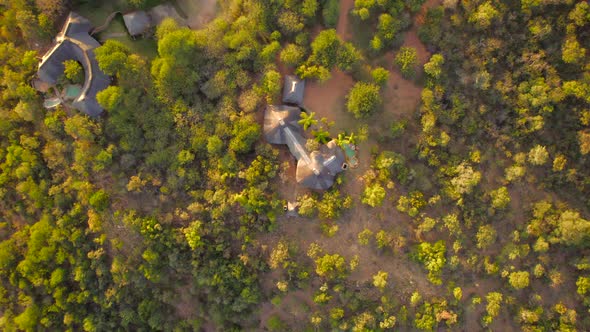 exclusive hotel chalets in South African preserved landscape, sunset hour. Aerial zoom out
