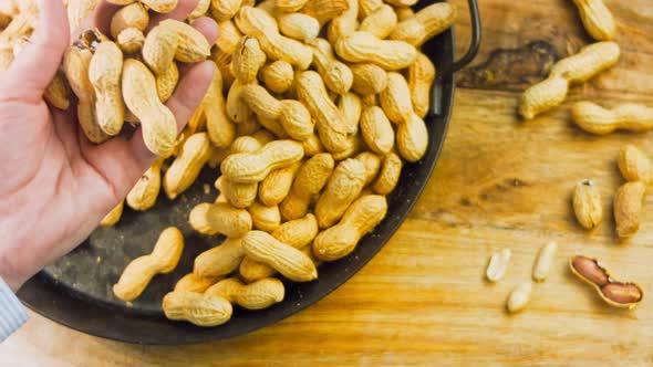 The Woman Analyzes the Quality of Peanuts with Bark