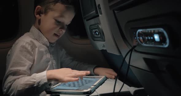 Boy with Pad in Plane. He Entertaining with Chess Game