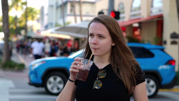 Young Pretty Woman Has a Cold Drink in the Sun of Miami Beach