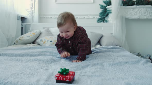 Slow Motion a Little Boy Crawls on the Bed for a Gift and Tries To Eat It