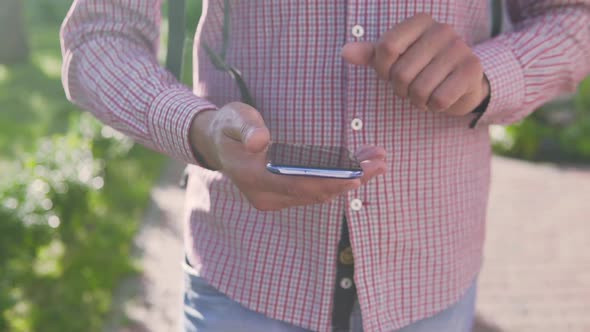 A man walks down the street and typing a message on the phone against the sunset