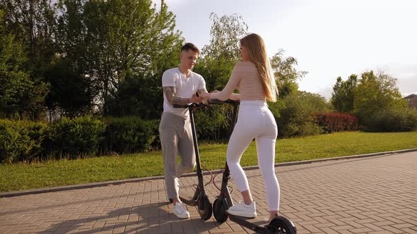 Teenagers Have Fun in the Summer in the Park and Ride Electric Scooters