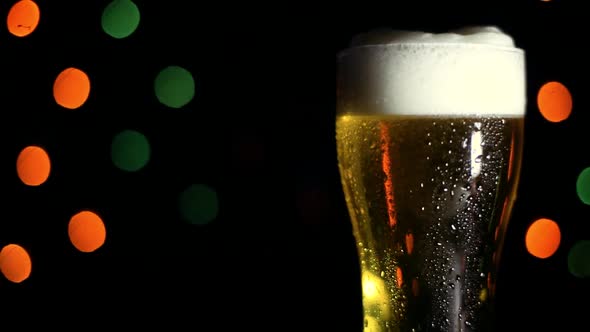 A Glass of Cold Beer on a Black Background with Colored Lights