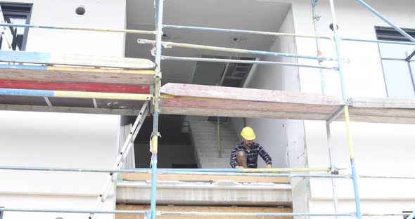 Construction worker using folding rule at construction site