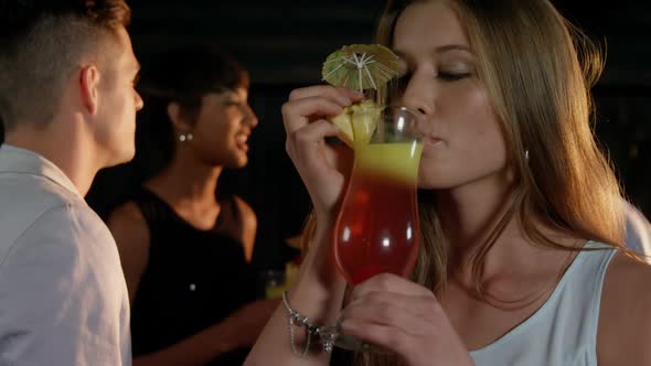 Beautiful young woman having a glass of cocktail in bar