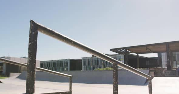 Low section of caucasian man riding and jumping on skateboard on sunny day