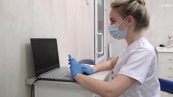 Dentist Assistant Working on Laptop Computer in Dental Clinic