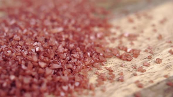 Red Hawaiian sea salt crystals falling in a heap on a wooden surface