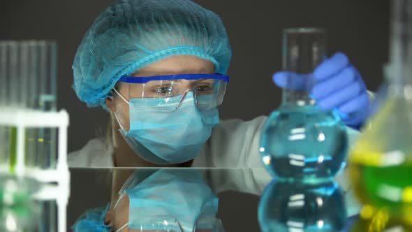 Scientist in Protective Uniform Looking at Blue Liquid in Flask, Water Analysis