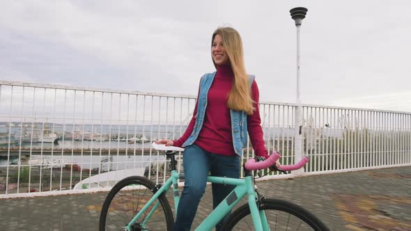 A Young Hipster Girl Standing with Fixed Gear Bike at City Centre on Bridge Slow Motion