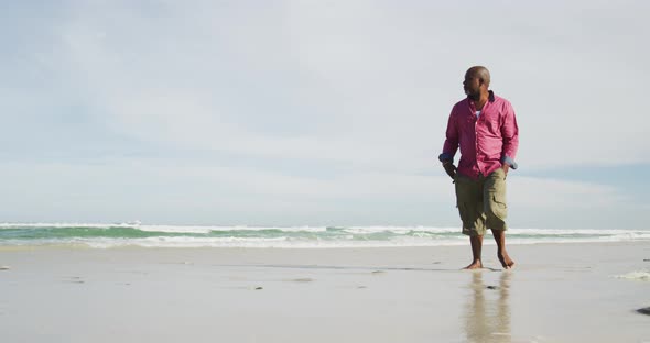 African american senior man walking on a beach looking at the sea