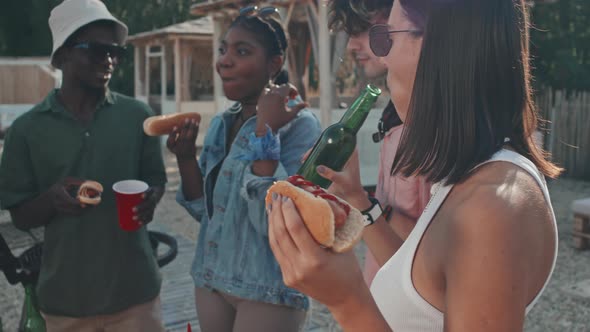 Girl Eating Hot Dog and Drinking Beer