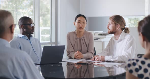 Multicultural Employees Talking at Team Meeting Sit at Conference Table