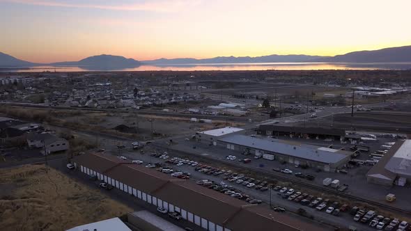 Flying backwards over industrial park at sunset as traffic moves