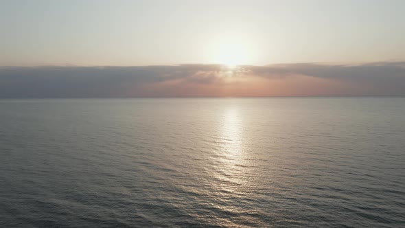 AERIAL: Flying Towards Sea with Sun Setting on a Horizon During Golden Hour