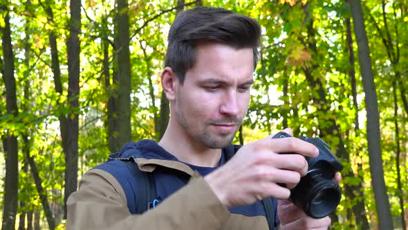 A Young Handsome Hiker Takes Pictures with a Camera in a Forest, Closeup