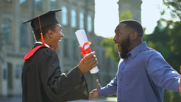 Excited Dad and Graduating Son Hugging Outdoors, Study Achievement, Education