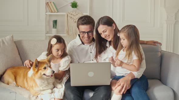 A Happy Family Uses a Laptop for Online Shopping, Sitting on the Couch at Home