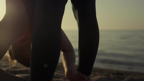 Athlete Girl Tilting Head to Feet Making Stretching Exercises on Beach Close Up