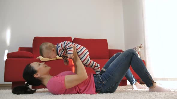 Mother Playing with Baby Son at Home Lifting Him