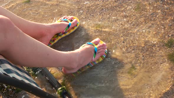 Girl's Legs with Flipflops Enjoying Seawaves