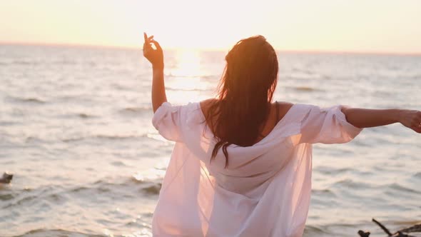 Beautiful Girl Dancing on the Beach in a White Shirt. Free Girl with Long Hair in a White Shirt