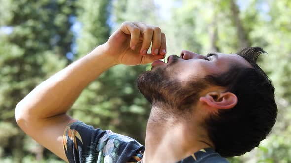 Slow Motion Shot of a man popping a cherry in his mouth and chewing on it.