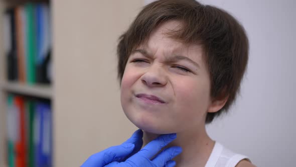 Headshot Portrait of Sad Caucasian Boy with Painful Throat Sitting in Hospital As Pediatrician Doing