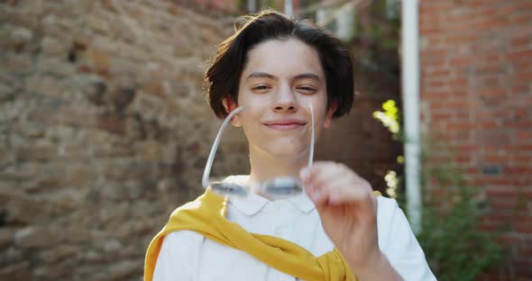 Slow Motion Portrait of Teenage Kid Taking Off Sunglasses Smiling Outdoors