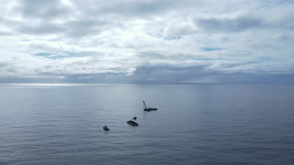 Large floating water crane installing a new artificial reef structure deep in the ocean.  Moving dro