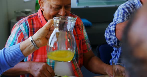 Senior woman pouring juice into glass to her friend 4k