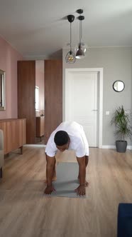 Front View of AfricanAmerican Man Practicing Burpee Exercise at Home Doing Push Ups and Jumping