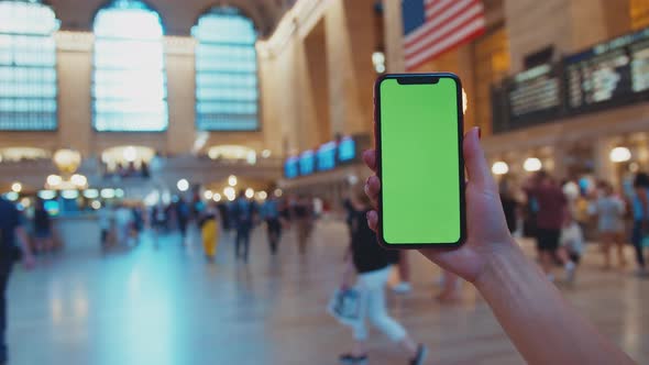 Female hand holding a smartphone with green display