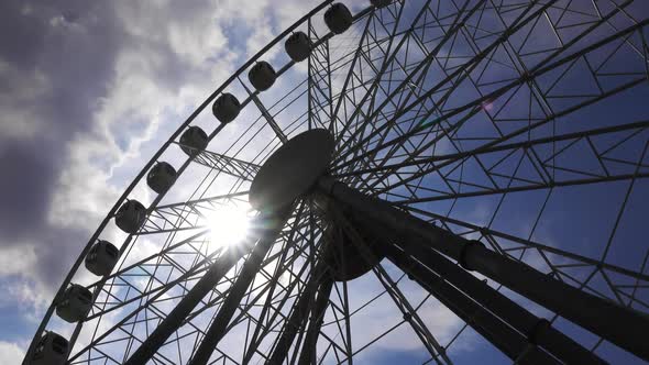 Ferris Wheel and Sun in Sky with Clouds