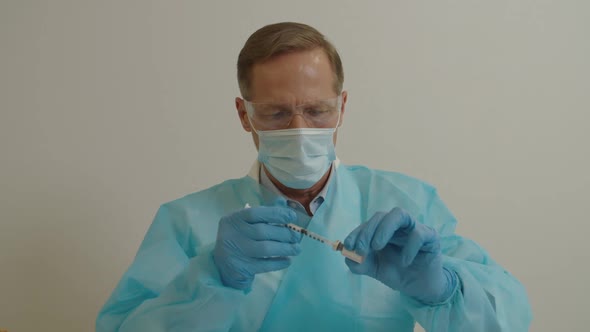 Serious Doctors in Ppe Holding Syringe and Coronavirus Vaccine Preparing for Injection at Clinic