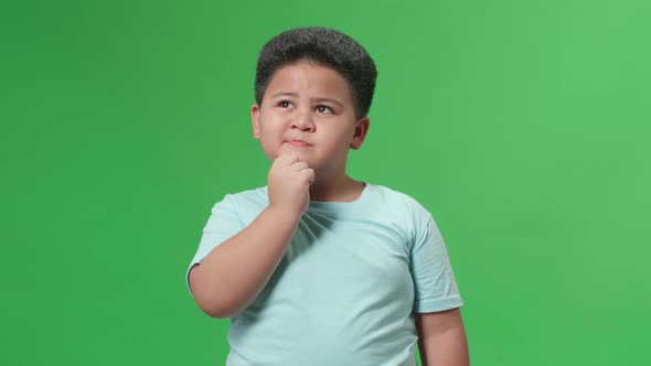 Asian Little Boy Thinking Something Then Raising His Index Finger On Green Screen In The Studio