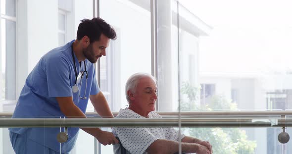 Doctor holding senior patient on wheelchair in passageway