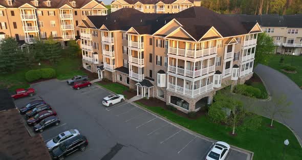 Modern new multistory apartment buildings in USA at golden hour. Aerial tilt up reveals balcony and