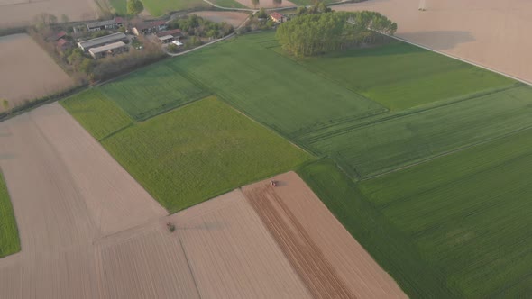 Aerial view: tractor working on cultivated fields, farmland from above