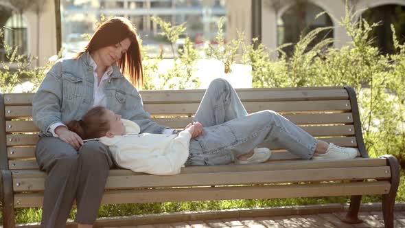 Full Length of Couple Sitting on Bench in Park and Enjoying Weekend Together