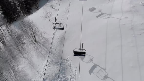 Aerial Top View of Ski Lift for Transportation Skiers on Snowy Ski Slope. Drone Flies Over Chair