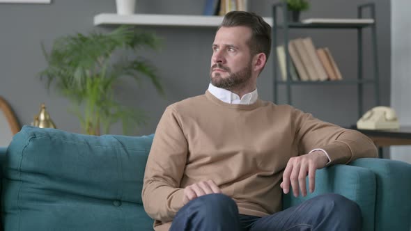 Man Thinking While Sitting on Sofa