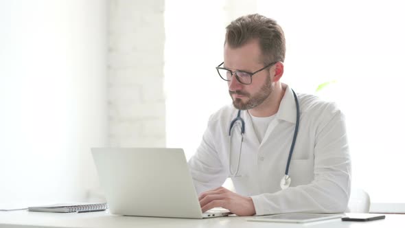 Doctor Showing Thumbs Up Sign While Using Laptop in Office